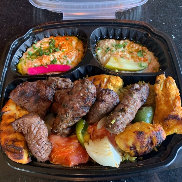 A Casablanca restaurant take-out container filled with grilled meats, rice, hummus, and baba ghanoush.