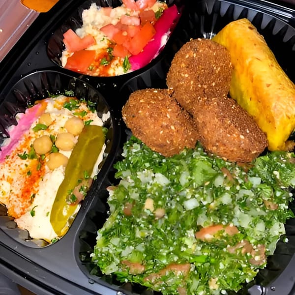 A Casablanca restaurant takeout container with falafel, hummus, tabbouleh, and a stuffed grape leaf.